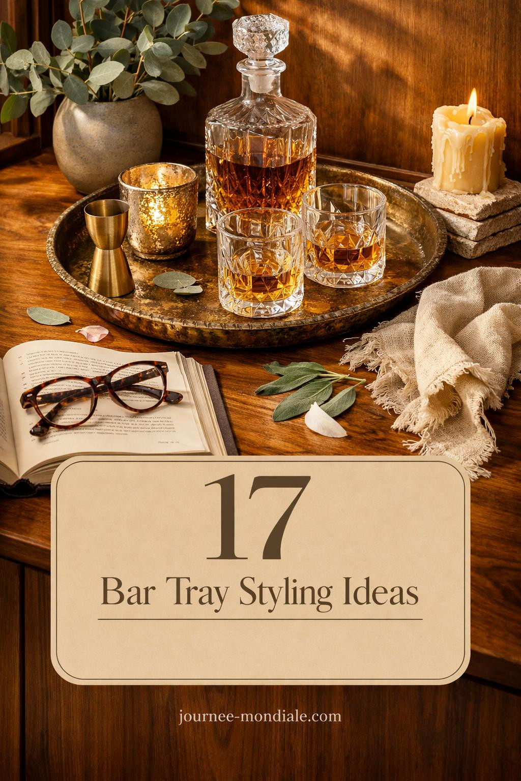 Sophisticated bar tray on walnut credenza with brass tray, crystal decanter, geometric glasses, eucalyptus, and cocktail book
