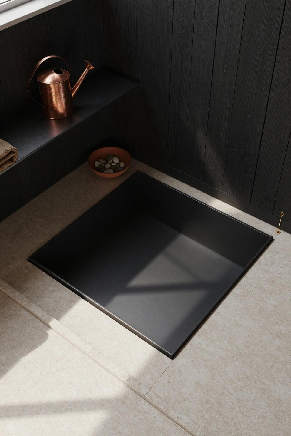 travertine bathroom - sunken matte black steel soaking tub recessed into cream travertine floor