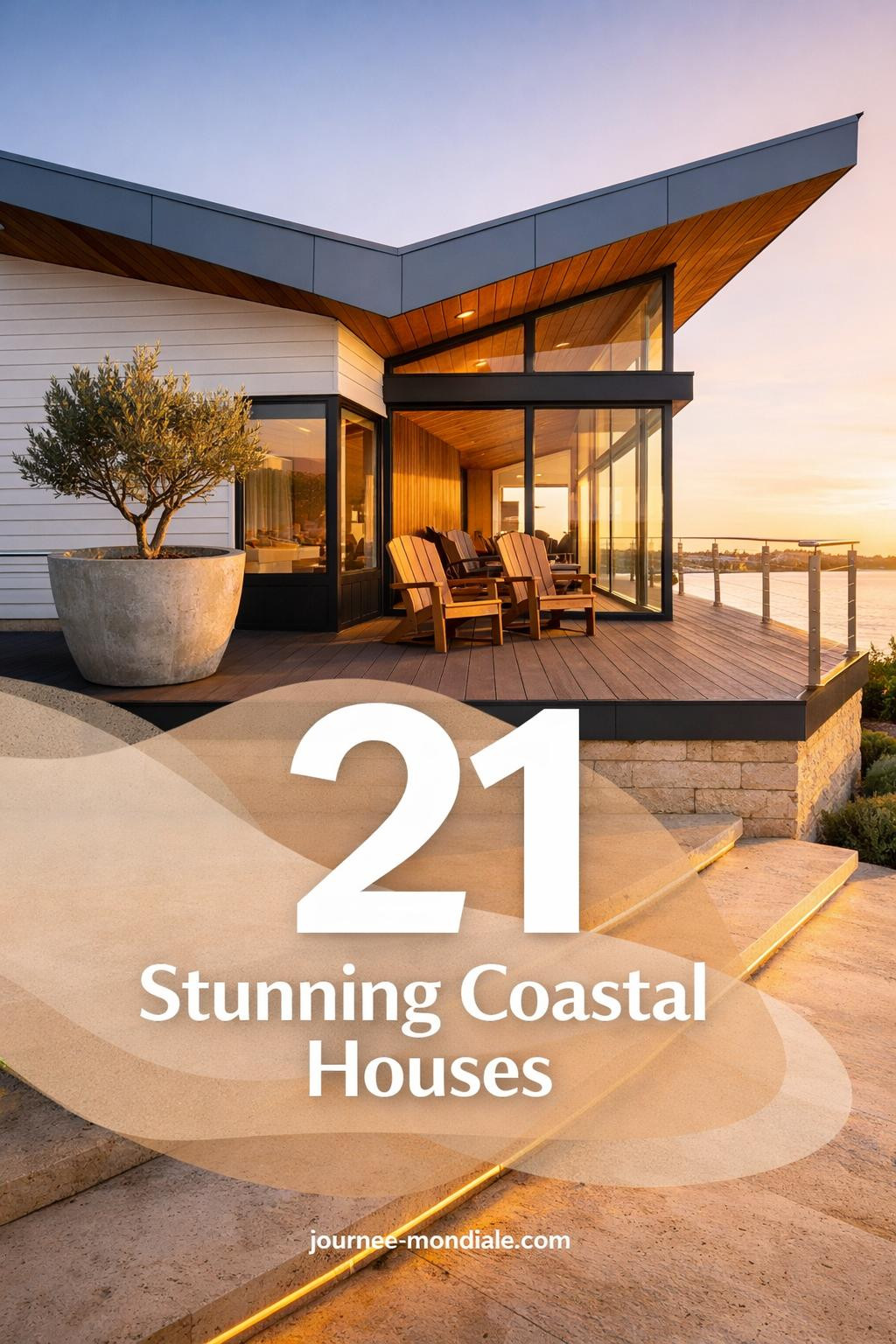 Modern coastal house exterior with white board-and-batten siding, charcoal deck, zinc butterfly roof, floor-to-ceiling glass walls, and teak furniture overlooking waterfront
