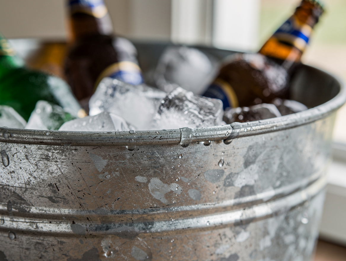 close-up detail of galvanized stock tank rim with condensation and beer bottles
