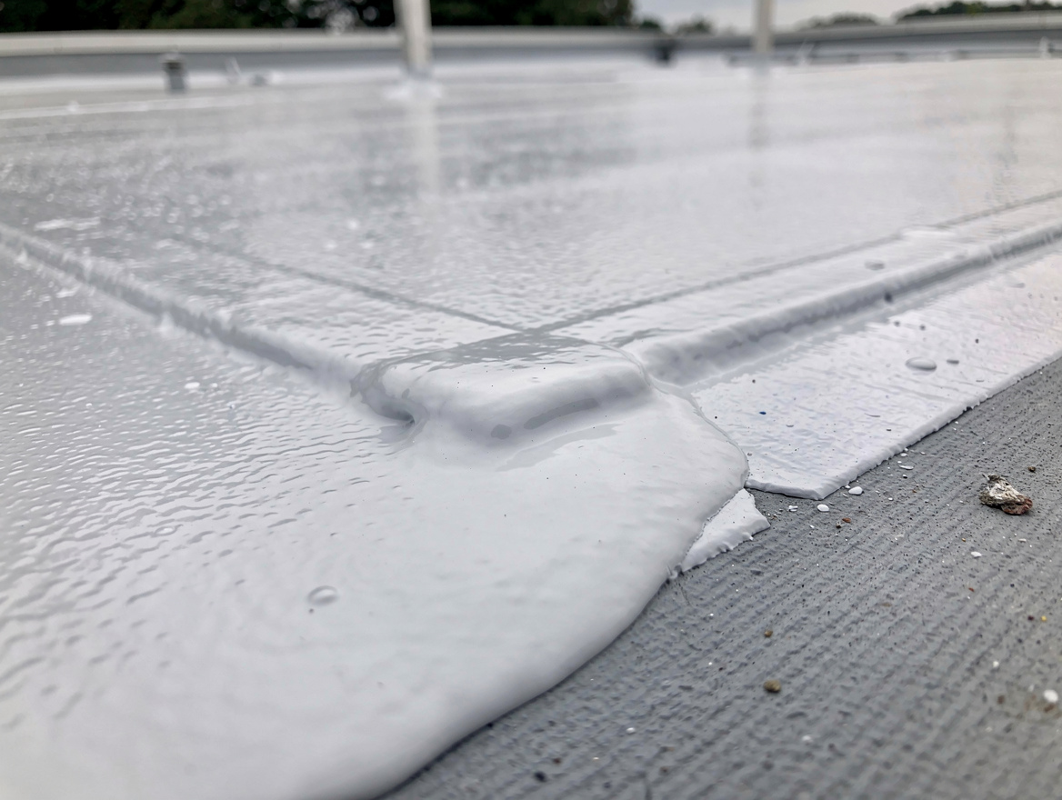 close-up detail of white elastomeric cool roof coating on flat garage roof, natu