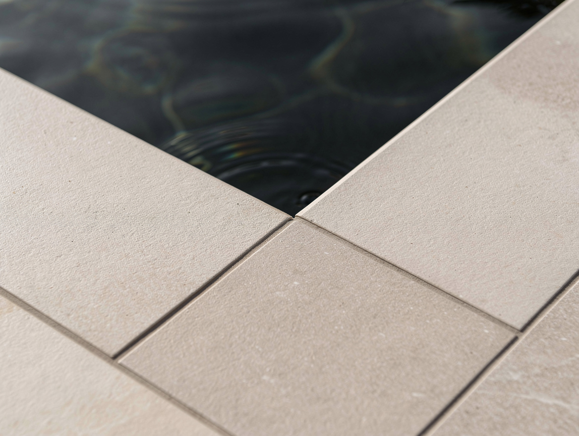 Close-up editorial photo of dark charcoal pool water meeting matte non-slip porc