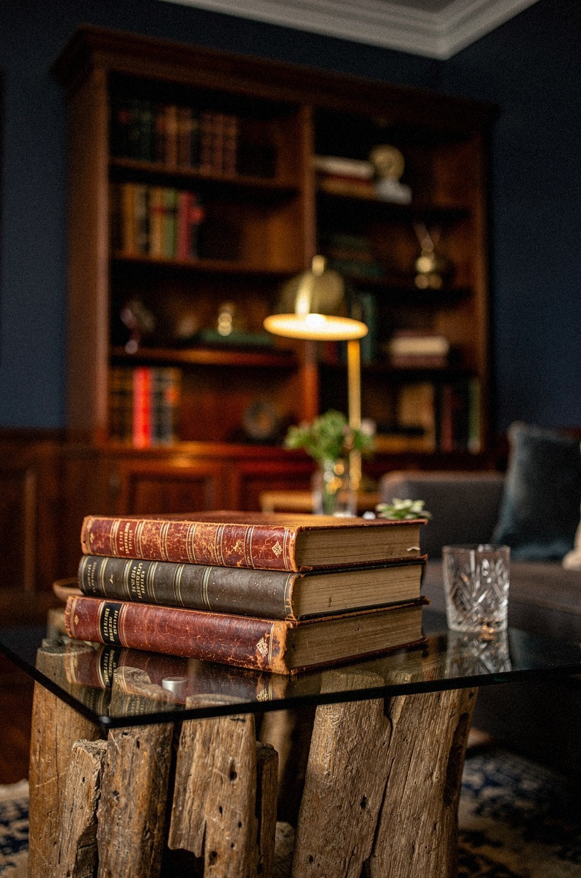 Stack leather-bound books beneath a glass-top side table