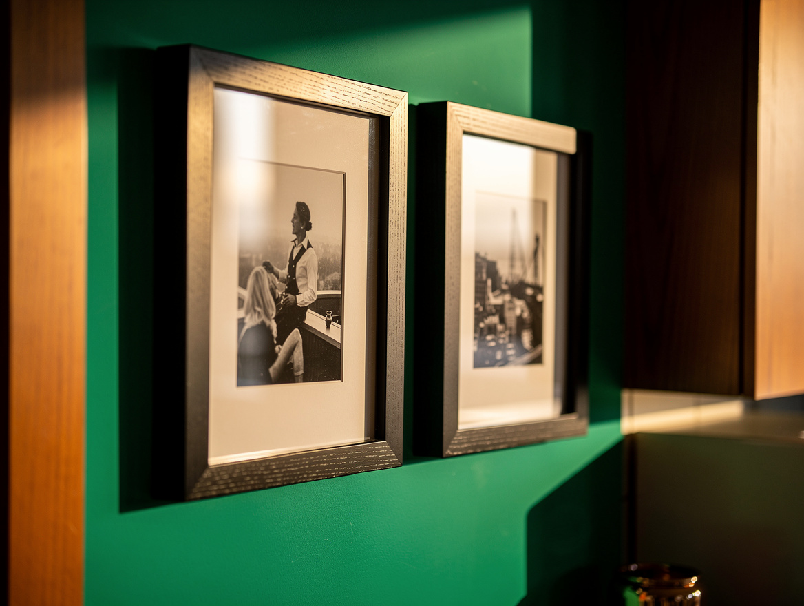 Close-up detail of two slim black wood frames with white mats and black-and-whit
