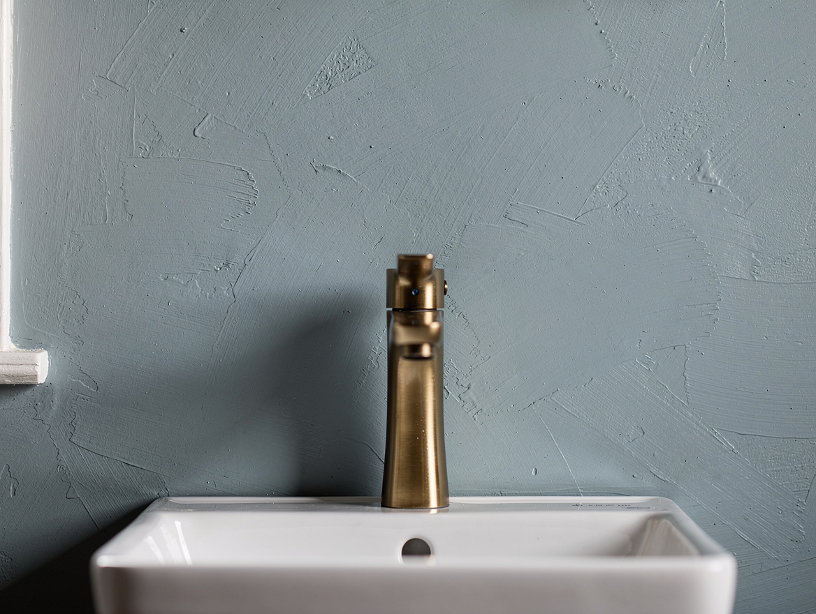 Close-up editorial photo of a painted bathroom vanity wall in dusty sea blue wit