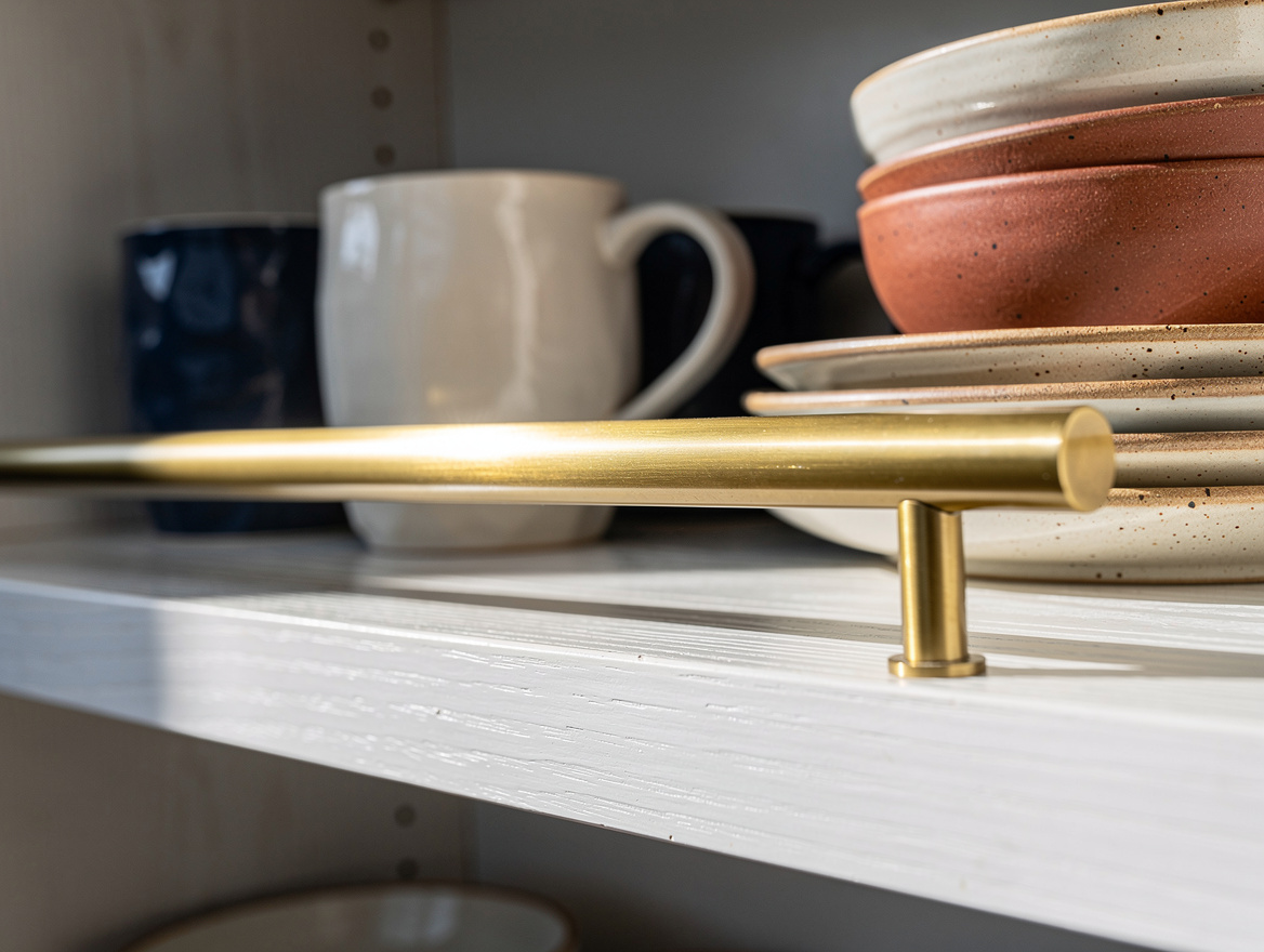Close detail photo of a white oak kitchen shelf with an unlacquered brass galler