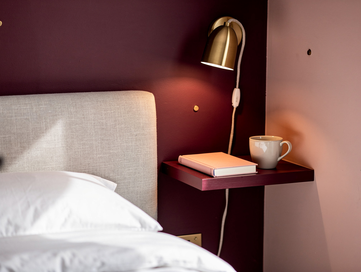 Close detail photo of a corner bed bedside wall, linen headboard, floating shelf