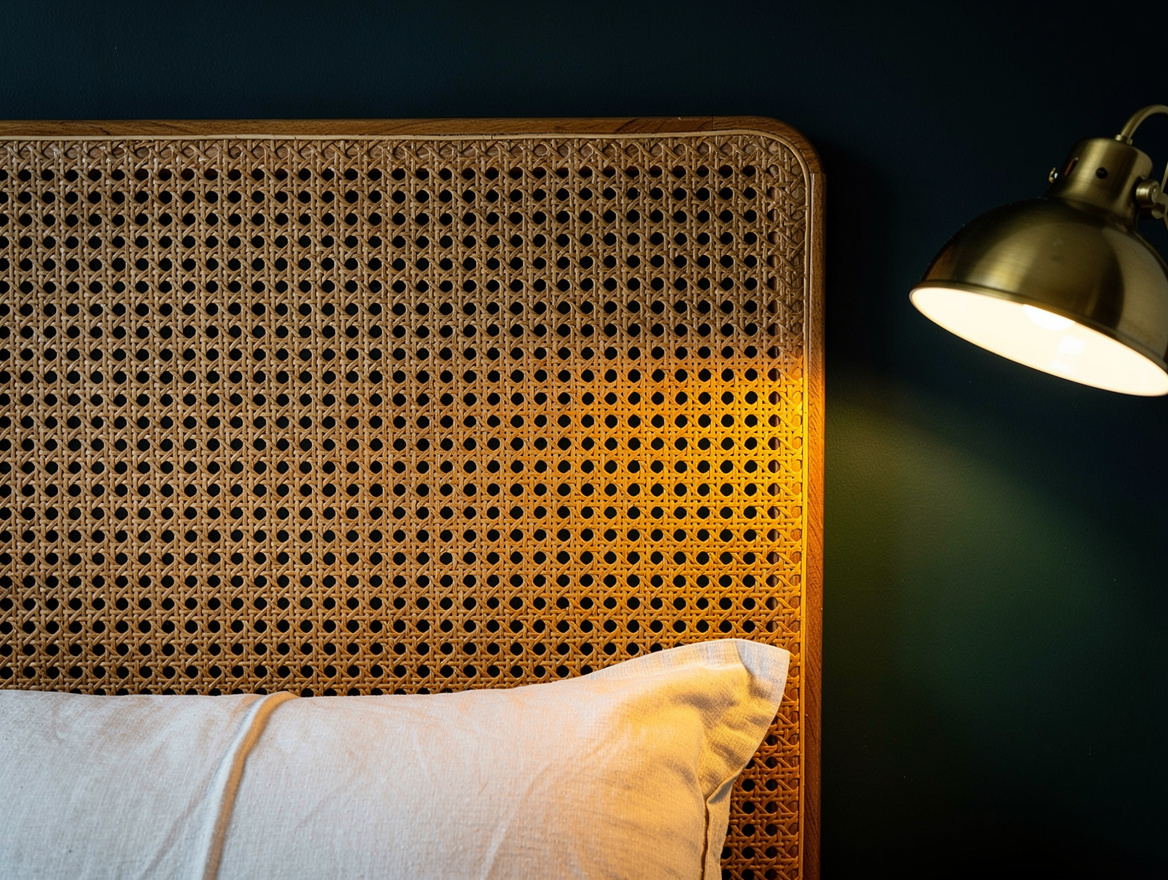 Close detail photograph of woven natural cane headboard against a matte navy wal