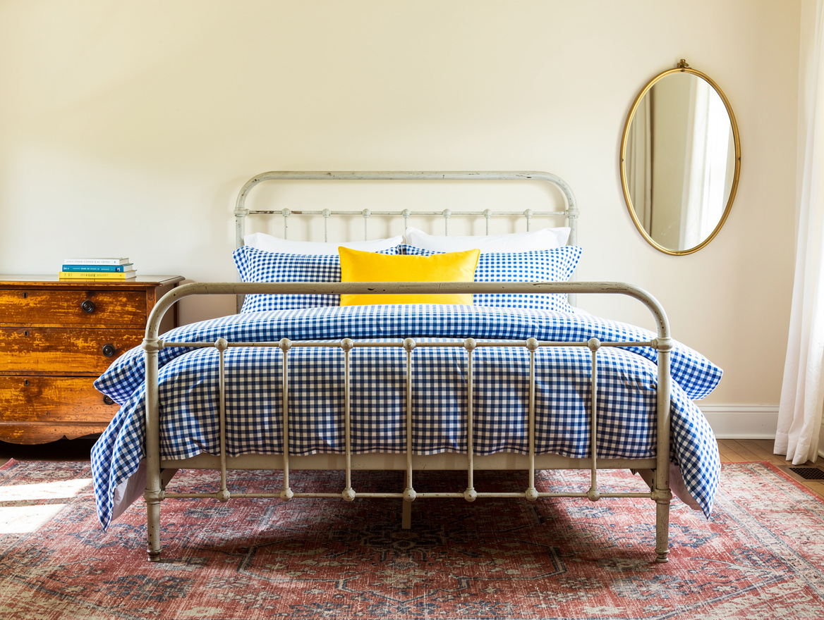 Wide atmospheric photo of a warm cream cottagecore bedroom with painted iron bed