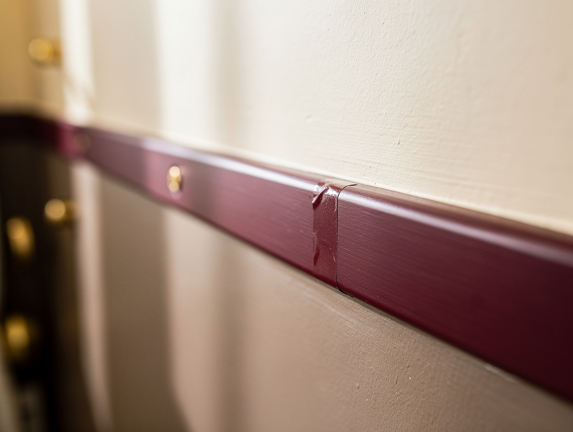 Close detail photograph of a crisp taped paint line meeting a painted MDF rail o