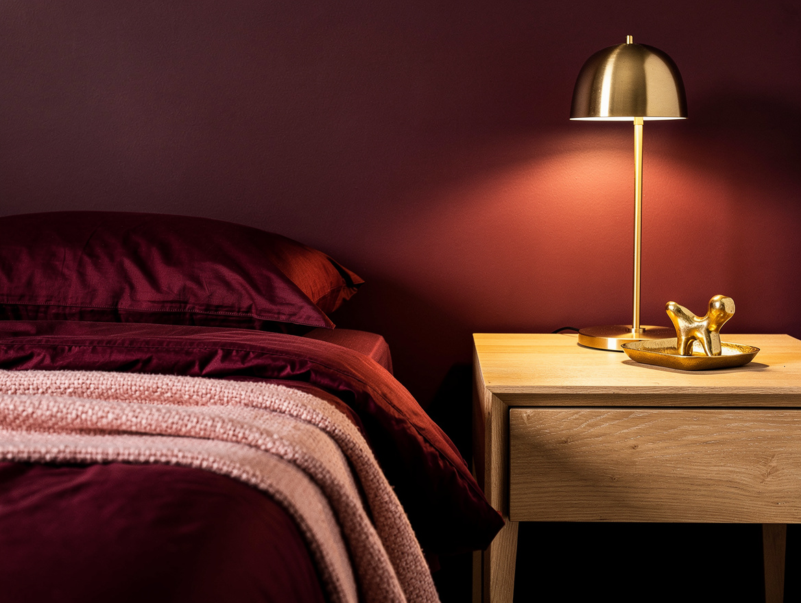 Realistic close-up editorial photo of monochromatic bedroom details: linen duvet