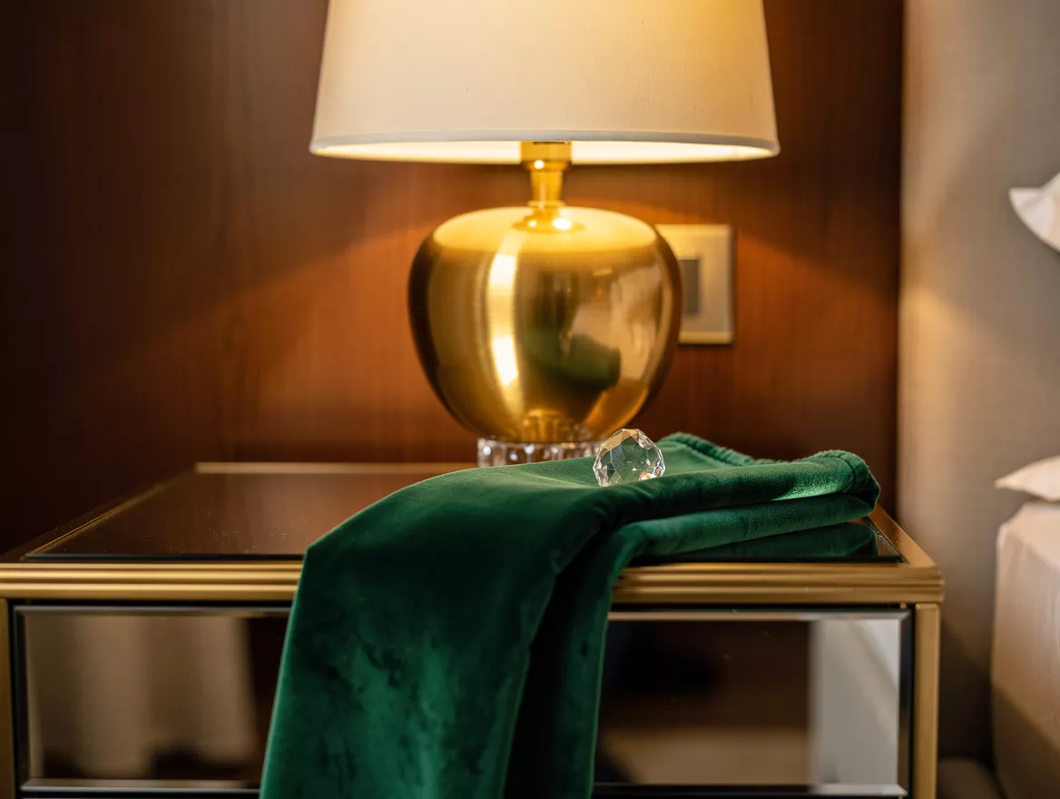 Realistic close-up editorial photo of a mirrored nightstand with a satin brass l