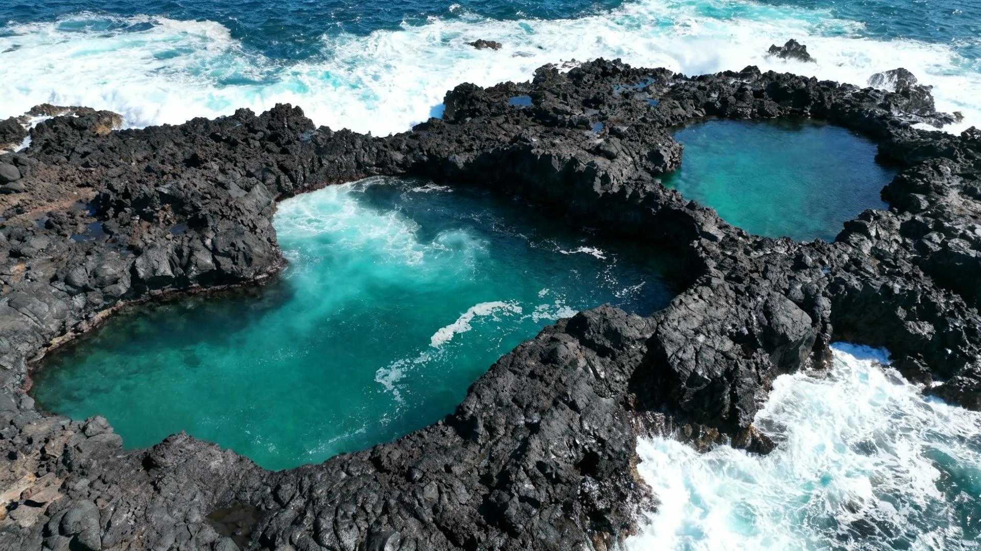 De Atlantische golf explodeert tegen zwart basaltgesteente terwijl wit schuim over natuurlijke zwembaden spat. Porto Moniz aan Madeira's noordwestkust verbergt een geologisch wonder: gratis toegankelijke lavazwembaden gevormd door 5 miljoen jaar vulkanische kracht. Geen entreepoorten, geen reserveringssystemen, alleen natuurlijk turquoise water dat contrasteert met donkere lavarotsen. Deze verborgen schat bewijst dat de spectaculairste natuurervaringen geen prijskaartje hoeven te dragen. Waar vulkanisch gesteente Atlantisch water vangt Porto Moniz ligt 60 km ten noordwesten van Funchal, verscholen in een bergachtige vallei waar dramatische lavakliffen de oceaan ontmoeten. Het dorpje van 1.700 inwoners overziet een kustlijn waar eeuwenlange erosie natuurlijke zwembaden heeft uitgeslepen in het basaltgesteente. Ilheu Mole, een oranjekleurige lavakoepel, rijst uit de oceaan met een 3 meter hoge vuurtoren die 62 meter boven zeeniveau staat. De natuurlijke pools liggen beschermd tussen deze rotswanden, waar Atlantische golven worden getemperd tot kalm zwemwater van gemiddeld 20°C. Het geologische wonder dat geen toegangsprijs kent Vijf miljoen jaar geleden ontstonden deze lavazwembaden toen gloeiende lavastromen de oceaan bereikten en abrupt afkoelden. Het contrast tussen het zwarte basaltgesteente en het kristalheldere turquoise water creëert een natuurlijk spektakel dat geen kunstmatige attractie kan evenaren. Drie gratis pools versus het betaalde complex De Piscinas Naturais do Aquário, Valhas en Cachalote blijven volledig gratis toegankelijk, gelegen bij het historische Fort João Batista uit 1730. Deze natuurlijke formaties bieden authentieke zwemervaring zonder commerciële faciliteiten. Het moderne Lido-complex, 500 meter westelijk, rekent € 3 entreegeld maar voorziet in lifeguards, kleedkamers en douches. Lokale gids Pedro Silva legt uit: "De gratis poelen zijn waar wij als kinderen zwommen. Geen poespas, gewoon genieten van de natuur." Fort João Batista: militair erfgoed naast natuurgeweld Het 18e-eeuwse fort beschermde Porto Moniz tegen piraten en huisvest nu het Aquário da Madeira. De toegang kost € 12, maar het uitzicht vanaf de fortwallen over de lavazwembaden is gratis. Het basaltgesteente toont duidelijke kolomstructuren, gevormd door snelle afkoeling van de lava. Zwemmen tussen lavaformaties voor € 0 De hoofdpoel bij Cachalote restaurant bereikt 2,8 meter diepte en biedt de beste snorkelmogelijkheden. Het water is zo helder dat je 5 meter diep tropische vissen kunt observeren tussen de zwarte rotswanden. Veiligheid volgens lokale vissers Een waarschuwingssysteem met gekleurde vlaggen signaleert zwemcondities. Groene vlag betekent veilig zwemmen, oranje waarschuwt voor golven, rood sluit de poelen bij gevaarlijke stroming. De beste zwemtijden zijn tussen 10:00 en 12:00 uur bij laagwater. Ana Mendes van de reddingsdienst adviseert: "Check altijd de live webcam op de gemeentelijke website voor actuele golfcondities. In november zijn de poelen meestal open, maar let op bij stormen." Wat te verwachten in november 2025 November brengt 120 tot 180 bezoekers per dag, tegen 1.200+ in de zomermaanden. De watertemperatuur daalt naar 19,5°C, maar de lagere zonstand creëert spectaculaire lichteffecten op het basalt. Geen cruise-schepen betekent authentieke rust voor fotografie. Wanneer zwart basalt goud gloeit Zonsondergang om 17:30 uur transformeert het water in vlammend oranje door reflectie op het vulkanische gesteente. Ochtendlicht tussen 08:30 en 09:30 uur kleurt de noordelijke rotsen goudkleurig, perfect voor fotografie zonder mensenmassa's. José Costa, 72 jaar en inwoner sinds 1951, herinnert zich: "Vroeger zwommen hier alleen locals. Nu komen mensen van over de hele wereld, maar de poelen blijven gratis. Dat is onze gift aan de wereld - oceanen van steen die iedereen kan delen." Jouw vragen over Porto Moniz, Madeira – natuurlijke lavazwembaden beantwoord Zijn de zwembaden echt volledig gratis toegankelijk? Ja, de Piscinas Naturais do Aquário, Valhas en Cachalote hebben geen toegangsprijs. Alleen het moderne Lido-complex rekent € 3 voor faciliteiten zoals kleedkamers en douches. De natuurlijke formaties zijn 24/7 vrij toegankelijk, behalve bij gevaarlijke golven. Wat is het beste seizoen om Porto Moniz te bezoeken? Mei tot september biedt warmste watertemperaturen van 21-23°C en kalmer weer. Oktober tot april toont dramatischer Atlantische golven maar koeler water van 18-19°C. November combineert milde temperaturen met minimale drukte - ideaal voor authentieke ervaring. Hoe verschillen deze pools van andere Madeira-attracties? Terwijl levada-wandelingen € 65 kosten voor begeleide tours en botanische tuinen € 10-15 entree rekenen, blijven Porto Moniz's natuurlijke zwembaden volledig gratis. Het dagbudget blijft onder € 40 inclusief parkeren en lunch, tegen € 60-90 in Funchal centrum. De laatste golf trekt terug terwijl avondlicht het basaltgesteente goudkleurig maakt. Porto Moniz bewijst dat 5 miljoen jaar vulkanische geschiedenis spreekt zonder prijskaartje - alleen geduld om te luisteren naar wat geen brochure kan beschrijven.