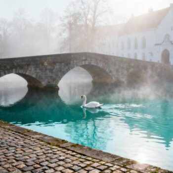 Het was 07:30 op een koude novembermorgen toen ik voor het eerst over de Minnewaterbrug liep. Mist hing boven het water, een eenzame zwaan gleed voorbij. Ik kwam naar Brugge voor nog een romantisch weekendje weg. Drie dagen later verliet ik de stad met een compleet ander begrip van wat echte romantiek betekent. De verwachting was simpel: middeleeuwse architectuur bekijken, wat foto's maken, typisch toeristisch weekend afvinken. De realiteit werd een onverwachte les over hoe een stad je relatie kan transformeren. Dag 1: Wanneer verwachtingen verdwijnen in ochtendmist Zaterdagochtend 08:15 betraden we het Begijnhof. Geen toeristen, alleen stilte en witte huisjes. De eerste les kwam onverwacht: Brugge's echte magie ontstaat niet in drukte maar in leegte. Om 10:00 verschenen de eerste groepen. Het contrast was adembenemend. De intieme sfeer verdween binnen minuten onder paardenkoetsen en selfie-sticks. We ontdekten het ritme van twee verschillende steden. Voor 09:00 behoort Brugge aan de lokale bewoners. Na 10:00 wordt het een openluchtmuseum. Deze timing zou onze volledige ervaring bepalen. De onverwachte lessen van Brugse straatjes Wat Brugge werkelijk leert over intimiteit en tijd werd pas duidelijk op dag twee. De stad is architecturaal geëngineered voor nabijheid. Elke hoek, elk bruggetje, elke geplaveide straat dwingt je tot langzamer lopen, zachter praten. Architectuur die tot fluisteren dwingt De straatjes zijn nauwelijks 3 meter breed. Huizen leunen naar elkaar toe alsof ze geheimen uitwisselen. Je kunt niet anders dan dicht tegen elkaar aan lopen. Het Begijnhof exemplificeert deze intimiteit. Dertig witte huisjes rondom een groen plein. Binnenin heerst automatisch stilte. Het ritme van 1.000 jaar geschiedenis Brugge dwingt je tot een ander tempo. Geplaveide straten maken haast onmogelijk. Middeleeuwse klokken slaan elk kwartier. We merkten hoe onze gesprekken veranderden. Minder plannen maken, meer in het moment zijn. De stad heeft zijn eigen tijdzone: Brugge Standard Time betekent "langzaam en bewust". Dag 2-3: Kleine rituelen die grote betekenis krijgen Zondag werd ons transformatiemoment. We ontdekten dat romantiek niet in grote gebaren zit maar in herhalende kleine rituelen. Ochtenden bij lokale bakkers Dagelijks ritueel om 08:00: verse Luikse wafels bij Bakkerij Otoole. De bakker, dezelfde plek sinds 40 jaar, kende elke stamgast bij naam. "Toeristen komen voor foto's," vertelde hij ons. "Echte liefde ontstaat in herhalingen, kleine gewoontes samen." Dit dagelijkse ochtendritueel werd onze favoriet. Avonden zonder plan Maandagavond verdwaalden we langs de Rozenhoedkaai. Geen reservering, geen schema. Spontaan belandden we bij chocolatier Dumon. De eigenaar, Pierre Dumon, liet ons proeven terwijl hij vertelde over 50 jaar ambacht. "Liefde en chocolade hebben hetzelfde geheim: geduld en de juiste temperatuur." Later die avond: onverwacht orgelconcert in de Basiliek van het Heilig Bloed. Toegang gratis, ervaring: onbetaalbaar. Het authentieke karakter van zulke momenten maakt het verschil. Wat Brugge onthult over romantiek De kernles kwam pas dinsdag: romantiek is geen checklist van activiteiten. Het is een omgeving die kwetsbaarheid en nabijheid toestaat. Brugge's unieke combinatie werkt als katalysator. Menselijke schaal (alles binnen 20 minuten lopen) plus wereldklasse schoonheid plus relatieve rust. Deze drie elementen creëren zeldzame ruimte voor echte connectie. We realiseerden ons: de beste momenten ontstonden spontaan. Niet tijdens geplande paardenkoetsrit (€ 50 voor 30 minuten) maar tijdens onverwachte ontmoetingen met locals. Jouw vragen over waarom Brugge de perfecte plek is voor een romantisch weekend beantwoord Wat maakt Brugge romantischer dan andere Europese steden? De unieke combinatie van wandelbare schaal en UNESCO-beschermde authenticiteit. Geen moderne architectuur verstoort de 15e-eeuwse sfeer. Plus relatieve rust: 8 miljoen bezoekers versus Venetië's 30 miljoen. Accommodaties kosten €130-€200 per nacht, 20% goedkoper dan Amsterdam. Authentieke stadservaring zonder toeristische commercialisatie. Wanneer is beste tijd voor romantisch weekend in Brugge? April-juni en september-oktober. Data toont 30-40% minder bezoekers dan zomer. Temperaturen rond 15°C, perfecte wandelweer. Bloeiende tuinen in Minnewaterpark. November 2025 biedt extra voordeel: kerstsfeer zonder kerstdrukte, chocoladefestival voorbereidingen, accommodatieprijzen nog laagseizoen. Is Brugge vergelijkbaar met Venetië? Vergelijkbare grachten-romantiek maar authentiekere ervaring. Venetië voelt als pretpark, Brugge als levende stad. Lokale bewoners wonen nog steeds in historisch centrum. Praktisch verschil: Brugge spreekt Nederlands/Engels, makkelijker bereikbaar vanuit Nederland (220 km vanaf Amsterdam). Minder toeristen-valkuilen, meer echte lokale cafés. Zondag 18:00, laatste blik vanaf het Belfort over rode daken en blauwe grachten. Besef: romantiek was niet in paardenkoets of restaurantreservering maar in elk spontaan moment dat Brugge's tijdloze atmosfeer ruimte gaf om werkelijk bij elkaar te zijn.
