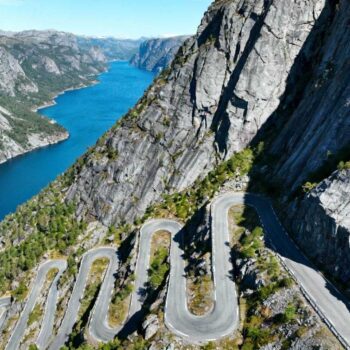 Wanneer de 340-graden haarspeldBocht van de Lysetunnel zich opent, verschijnt 1.000 meter beneden je de azuurblauwe Lysefjord. Je bent net acht van de 27 legendarische haarspeldbochten gepasseerd. Lysebotn wacht beneden, het rustige eindpunt van Noorwegens meest spectaculaire bergweg. Terwijl cruise-passagiers € 180 betalen voor een 3-uur pakket met vaste schema's, ontdek je de Lysevegen op eigen tempo voor € 120 per dag. Complete controle over timing, stops en de 5 viewpoints die bussen missen. Van Amsterdam naar Lysebotn: de 1.250 km strategie De reis van 1.250 km vanaf Amsterdam vereist strategische planning. Drie hoofdroutes leiden naar Lysebotn: directe autoroute via Stavanger (15 uur rijden), veerboot-combinatie via Forsand (13 uur inclusief 2u20m boottocht), of vlieg-plus-huur via Stavanger Airport. De cruciale factor: de Lysevegen opent seizoensgebonden eind mei en sluit in november bij sneeuwval. GPS-coördinaten 58.9547°N, 6.5940°E markeren je eindbestemming. In wintermaanden bereik je Lysebotn uitsluitend per veerboot vanuit Forsand. Net als de Flåmsbana vereist timing alles. Plan aankomst tussen 26 mei en 28 oktober voor gegarandeerde wegtoegang. Timing en kosten: het mei-september venster Slimme timing levert € 155 accommodatiebesparing op. Mei-accommodaties kosten € 80-120 in guesthouses, augustus-prijzen schieten naar € 150-250 door cruise-invasie. De sweet spot: laatste week mei wanneer sneeuwwanden nog 3-4 meter hoog staan maar de weg net open is. Dagelijkse kosten breakdown Transparante budgettering: accommodatie € 95-165 (Lysebotn Fjellstue), maaltijden € 22-35 (Lysefjorden Kafé), veerboot € 15-40 afhankelijk van route. Totaal € 120-185 per dag voor authentieke meerdag-ervaring. Vergelijk dit met € 180 cruise-pakket met 3-uur tijdslimiet. Zelfstandig betekent overnachting tussen de 120 inwoners, ochtendroutine observeren, verse vis kopen bij lokale vissers om 07:00. Verkeersstrategie per seizoen Mei: 200-300 voertuigen per dag, rustigste maand. Augustus: 800-900 voertuigen, drukte tussen 08:00-19:00. Vergelijkbaar met het 250-zielen dorp Å, vermijd weekends in juli-augustus. De 27 haarspeldbochten navigeren: 5 essentiële stops De Lysevegen-ervaring transformeert een technische rit in bergontdekking. 20 kilometer traject, 932 meter hoogteverschil, gemiddelde rijtijd 1u15m. Gebruik lage versnelling bij afdaling, vooral bij de onderste 10 bochten waar bussen moeite hebben. Startpunt Sirdal tot Lysetunnel Het laatste tankstation bevindt zich in Ålgård, 45 km voor Lysebotn (€ 1,75/liter). De iconische Lysetunnel met 340-graden bocht biedt het eerste adembenemende fjord-panorama. Fotomoment gegarandeerd, verkeersdrukte tip: arriveer vóór 10:00 of na 16:00. Nieuwe viewpoint "Råså Vista" opent juli 2025 bij de tunnel. 20 extra parkeerplaatsen bij Øygardstøl voor wie de 2 km wandeling naar Kjeragbolten-trailhead wil maken. Lokale ervaringen: Kjeragbolten toegang Lysebotn fungeert als basecamp voor de 6 km wandeling naar Kjeragbolten op 1.084 meter hoogte. Gratis toegang tot de beroemde rots tussen twee kliffen. Net als in de Alpen geldt timing: vroege ochtend voor lege routes. "Kom voor 09:00 aan als je rustig wilt rijden. Na 11:00 wordt het druk met bussen," legt Ole Hansen uit, inwoner van Lysebotn sinds 1998 en eigenaar van Lysebotn Fjellstue. Wat cruise-toeristen missen: de lokale Lysebotn-ervaring Cruise-bezoekers krijgen 3 uur. Zelfstandige reizigers ontdekken de Lysegården boerderij, kopen verse zeebaars direct van vissers (€ 22/kg, beste tijd 07:00-09:00), proeven gjetost (bruine kaas) voor € 8/200g. De Lysefjord Waterkrachtcentrale uit 1985 biedt rondleidingen op aanvraag (minimum 10 personen). Interactieve tentoonstelling toont hoe 1.200 GWh per jaar wordt opgewekt. Net als de Bodensee-route onthult mei-september de beste lokale ervaring. "De beste tijd voor verse vis is tussen 07:00 en 09:00, wanneer vissers terugkeren. Vraag naar 'fisk fra morgon' voor versheidsgarantie," vertelt Elin Berg, visser in Lysebotn sinds 2005. Jouw vragen over Lysebotn, Noorwegen – eindpunt van een epische weg beantwoord Is de Lysevegen gevaarlijk voor onervaren bestuurders? 27 haarspeldbochten vereisen focus maar geen speciale vaardigheden. Weg goed onderhouden, verkeer gematigd buiten juli-augustus. Belangrijkste tip: rem op motor in lage versnelling bij afdaling. Moeilijkheidsgraad 7/10, vergelijkbaar met Transfăgărășan. Wat zijn de lokale specialiteiten in Lysebotn? Verse zalm en kabeljauw rechtstreeks van vissers, rendiergerechten (€ 32/maaltijd, seizoensgebonden oktober-mei), bruine kaas gjetost gemaakt met geitenmelk. Eén restaurant/café, dus zelf-catering voor avonden praktisch. Inkopen in Stavanger voor aankomst. Hoe verhoudt Lysevegen zich tot Trollstigen? Lysevegen: 27 haarspeldbochten vs Trollstigen's 11, 185.000 jaarlijkse bezoekers vs Trollstigen's 650.000. Minder bekend betekent 61% minder verkeersdrukte. Direct fjord-toegang en combineerbaar met Kjeragbolten-wandeling. Accommodatie 18% goedkoper dan Trollstigen-gebied. Stilte bij Lysefjord om 22:00 in juni, middernachtzon die rode vissershutten kleurt. Enkel geluid van water tegen 1.000-meter kliffen. De beloning voor wie 27 bochten neemt in plaats van het 3-uur cruise-pakket.