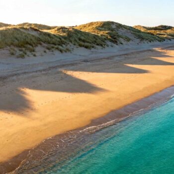 Augustus 14:00 op Zoutelande strand — parasols zo ver het oog reikt, parkeerplaatsen vol, hotels vanaf € 150 per nacht. Maar stel je voor: mei om 08:00, identieke 18°C temperatuur, leeg strand, dubbel zoveel ruimte om te ademen en accommodaties voor € 90. Zoutelande's zuidelijke ligging aan Walcheren creëert een verborgen timing-geheim dat 88% van bezoekers mist. De "Nederlandse Rivièra" bijnaam is geen marketing-romantiek maar geologische realiteit. Tussen mei en september biedt deze kustplek identieke weersvoordelen als juli-augustus, maar met radicaal verschillende ervaring. De zuidelijke ligging die alles verandert Zoutelande ligt uniek aan de zuidkant van schiereiland Walcheren. Deze oriëntatie vangt meer zonlicht dan andere Nederlandse stranden — gemiddeld 1.700 zonne-uren per jaar versus 1.500 landelijk gemiddelde. De 20 meter hoge duinen fungeren als natuurlijke windschermen. Waar Scheveningen en Zandvoort directe noordwestenwind ontvangen, geniet Zoutelande van 30% lagere windsnelheden. Resultaat: watertemperaturen 2°C warmer dan noordelijke kustplaatsen. In september bereikt de Noordzee hier nog 18°C, terwijl andere stranden al afkoelen naar 16°C. Scheveningen kent vergelijkbare timing-voordelen maar mist deze microklimaat-bescherming. Mei-juni: het verborgen hoogseizoen Terwijl toeristen wachten op juli, ervaren lokale bewoners mei als het echte seizoen. Temperaturen schommelen tussen 16-20°C met 7 zonne-uren per dag — meteorologisch identiek aan augustus. Weersvoordelen zonder drukte De Catharinakerk uit 1270 fotograferen zonder wachtrijen. De Korentmolen van 1722 bezoeken terwijl de molenaar rustig uitlegt hoe graankorrels worden gemalen. Het strand om 08:00 voor jezelf hebben, met alleen het geluid van opkomende golven. Accommodatieprijzen dalen dramatisch: B&B's kosten € 90 versus € 150 in augustus. Restaurants hanteren laagseizoentarieven — verse mosselen voor € 15 in plaats van € 25. Lokale ritmes ontdekken Woensdagochtend weekmarkt van 08:00-12:00 zonder toeristenmassa's. Lokale vissers delen verhalen bij strandpaviljoen De Branding om 10:00, terwijl koffie nog € 2,50 kost in plaats van € 4. Zoals Frank de Munck, reisblogger bij "Zeeuwse Parels", benadrukt: "Zoutelande blijft een verborgen juweel met zijn unieke zuidelijke ligging, rust en heerlijke stranden die veel authentieker aanvoelen dan in de Randstad." De authentieke Zeeuwse bolus krijgt tijd en aandacht van lokale bakkers — geen gehaaste productie voor hongerige massa's maar ambachtelijke bereiding voor € 2,50. September: mediterrane nazomer September onthult Zoutelande's beste geheim. Luchttemperatuur blijft 18-20°C maar de Noordzee bereikt jaarlijks maximum van 18°C na maandenlange zomerse opwarming. Optimale strand-condities Zuidelijke ligging vangt langere avondzon tot 20:30 — het gouden uurtje strekt zich uit over twee uren. Hotels hervinden evenwicht bij € 100 per nacht, restaurants keren terug naar ontspannen ritmes. Van Sint Willibrordsput, herbouwd in 1980, valt om 19:00 oranje gloed over de Noordzee te bewonderen. Het strand leegt maar behoudt zijn warmte — ideaal voor avondwandelingen door fietsroutes die vakantie-gevoelens oproepen zonder € 275 hotelkosten. Culturele diepte-momenten Locals keren terug naar hun strand na de hoogseizoen-exodus. Walcherse Dagen brengen streektradities tot leven zonder commerciële drukte. Catharinakerk orgelconcerten op zondagmiddag om 15:00 — gratis toegang, authentieke kerksfeer. Marijke Vos, toeristisch manager VVV Walcheren, bevestigt: "De combinatie van cultuur, natuur en voorzieningen maakt Zoutelande een favoriete bestemming voor gezinnen en rustzoekers." Juli-augustus versus mei-september: het grote contrast Strand capaciteit juli: 15.000 dagbezoekers versus 2.000 in mei. Parkeren juli: 30 minuten wachttijd versus direct beschikbaar in mei. Restaurant reserveringen juli: verplicht 2 weken vooruit versus mei walk-in welkom. Accommodatie kostenverschil: € 60 per nacht tussen piekseizoen en mei-september. Emotioneel verschil nog groter — juli betekent gehaaste efficiency, mei-september biedt ontspannen ontdekking. Weersdata bewijst het: mei-september zijn meteorologisch equivalent aan juli-augustus. Maar de ervaring transformeert compleet. Vergelijk met Bretagne dat € 155 besparing biedt in dezelfde maanden. Jouw vragen over Zoutelande, Nederland – de Nederlandse Rivièra beantwoord Wat zijn exacte kosten mei versus augustus? Mei: accommodatie € 90 gemiddeld B&B, restaurant € 15-20 maaltijd, parkeren gratis langs boulevard. Augustus: accommodatie € 150, restaurant € 25-30, parkeren € 15 per dag tijdens piekmomenten. Totaal dagbudget verschil: € 60-80 voor twee personen. Hoe bereik ik Zoutelande optimaal in mei-september? Auto via A58-N57 duurt 1,5-2 uur vanaf Rotterdam-Amsterdam, parkeren overal beschikbaar. Trein naar Vlissingen plus bus 53 kost € 20-30 retour, elk uur vertrek. Fietsoptie: 15 km vanaf Middelburg, vlak terrein, verhuur € 15 per dag. B&B ervaringen bieden authenticiteit die € 200+ hotels missen. Waarom verkiezen Zeeuwen mei boven juli? Locals vermijden juli-augustus drukte bewust. Mei biedt "Zeeuws licht" — de schilders-traditie van Mondriaan — zonder massa's, authentieke dorpsritmes, betere restaurantservice zonder stress, en mogelijkheid tot echte gesprekken met locals die tijd hebben voor verhalen. September 07:30 op het strand. Helmgras buigt in zachte zeewind, Noordzee glinstert zilver-blauw, voetstappen in nat zand verdwijnen met eb. Dit is Zoutelande zoals 1.200 inwoners het koesteren — vijf maanden per jaar beschikbaar, maar alleen ontdekt door wie timing boven traditie kiest.