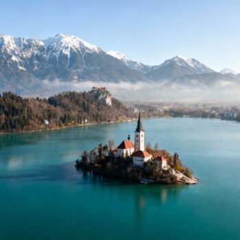 Augustus in Zermatt betekent €340 hoteltarieven en wachtrijen bij de Gornergrat-baan. Dertig miljoen bezoekers verdringen zich jaarlijks op Zwitserse bergpaden. Verschuif 1.100 km naar Ljubljana en ontdek €95 accommodatie, lege Julian Alpen-trails en slechts 5 miljoen bezoekers. Slovenië elimineert de keuze tussen Zwitserland en Oostenrijk door beide te overtreffen op authenticiteit, toegankelijkheid en waarde. Dit 20.273 km² compacte land vangt Alpenschoonheid, mediterrane kust én ondergrondse wonderen zonder de massa-toerisme premie. Wanneer Alpenschoonheid 70% goedkoper wordt zonder concessies De Julian Alpen bereiken 2.864 meter met Triglav tegenover Zwitserland's 4.478 meter Matterhorn. Het landschap voelt identiek: smaragdgroene valleien, gletsjermeren, bloeiende alpine flora. Het verschil zit in toegankelijkheid en prijs. Lake Bled ligt 54 km van Ljubljana, Postojna-grotten 50 km, Adriatische kust Piran 120 km. Zwitserland verspreidt hoogtepunten over 41.285 km² — Slovenië comprimeert vergelijkbare verscheidenheid in de helft. Accommodaties kosten €70-120 per nacht versus Interlaken €180-275. Maaltijden variëren van €10-20 versus €25-40 in Zwitserland. Nationaal park toegang kost €10-15 tegen Zwitserse €40-60. De wiskundige logica blijkt helder: 20-30% lagere kosten bij gelijke visuele impact. De geografie die twee landen combineert in één weekend Bergmajestuositeit zonder Zwitserse prijsschok Triglav National Park (880 km²) weerspiegelt Zwitserse Alpenesthetiek met turquoise Soča rivier en verticale bergwanden. Gentiaanvelden bloeien mei tot september tussen kristalheldere bergbeken. Vogel Ski Resort op 1.535 meter biedt wintersporten voor €35 dagpas versus Zermatt €80. De 54 km afstand tussen Bled en Bohinj creëert variatie zonder logistieke hoofdpijn. Beide meren liggen op 30 minuten rijden en bieden identieke postkaartperfectie als Zwitserse concurrenten. Mediterrane kust die Oostenrijk mist Piran's 46 km Adriatische kustlijn transformeert Slovenië van puur Alpenland naar hybride bestemming. Venetiaanse architectuur stamt uit de 13e eeuw. Verse zeevruchten kosten €12-18 versus €30+ in Zürich restaurants. Zonnige 28°C zomers combineren bergfrisse ochtenden met mediterrane middagen. Deze geografische bonus — bergen én zee binnen 2 uur rijden — overtreeft beide buurlanden afzonderlijk. Geen andere Alpenbestemming biedt deze verscheidenheid binnen zo'n compact gebied. Wat 2,1 miljoen locals dagelijks ervaren dat 88% bezoekers mist Duurzaamheidsmodel als cultureel DNA Slovenië's Green Scheme certificeert sinds 2016 meer dan 60 bestemmingen op milieu-impact. Locals fietsen door Ljubljana via 176 km gratis fietsnetwerk sinds 2011. Het land beschermt 53% natuurgebieden en beperkt toeristengroepen tot 25 personen in Postojna-grotten. Dit weerspiegelt nationale identiteit sinds 1991 onafhankelijkheid, geen marketing-truuk. Vergelijk met Zwitserland's commercialisering van Jungfraujoch waar treinkaartjes €200 kosten. Zoals Eva Marolt van VVV Tourism Slovenia bevestigt: "Met 9% groei in toerisme laat Slovenië zien dat duurzaam reizen samengaat met economische groei." Culinaire fusie die alpine traditie ontmoet Kranjska klobasa (Sloveense worst sinds 1896) en žlikrofi (gevulde deeg uit Idrija, UNESCO sinds 2022) definiëren lokale keuken. Rebula en Teran wijnen kosten €3-8 per glas in lokale kroegen. De combinatie van Oostenrijkse hartigheid, Italiaanse finesse en Balkaanse smaakprofielen creëert unieke gastronomie. Ljubljana's Odprta Kuhna markt opent elke vrijdag maart tot oktober. Vijftig kraampjes serveren gerechten van €5-12 zonder toeristische prijsopslag. Ana Novak, eigenaar eco-lodge Bled, legt uit: "Gasten waarderen de rust en natuurbehoud, iets dat andere Alpengebieden snel verliezen." Waarom mei-september Slovenië's bezoekers slim verspreiden Beste bezoektijd loopt mei tot september met 20-30°C temperaturen. Bloeiende Alpen, zwembaar Bled juni-augustus, perfecte Adriatische kust juli-september. Juli markeert hoogseizoen maar drukte blijft relatief: 5 miljoen jaarlijks versus Zwitserland 30 miljoen betekent 83% minder mensenmassa's. November-maart vormt laag seizoen met wintersporten december-maart in 7 skigebieden. Schengen-lidmaatschap sinds 2023 elimineert grenscontroles en nieuwe treinverbinding Innsbruck-Ljubljana verbetert bereikbaarheid verder in 2025. Vliegen Amsterdam-Ljubljana duurt 1,5-2 uur voor €150-250 retour. Geen vignet nodig zoals Zwitserland's €43,35 verplichte snelwegpas. Jouw vragen over waarom Slovenië het nieuwe Zwitserland is beantwoord Welk accommodatiebudget moet ik verwachten vergeleken met Zwitserland? Laag segment hostels en guesthouses kosten €30-50 versus Zwitserland €60-90. Middenklasse 3-sterren hotels variëren €70-120 versus €150-250. Hoog segment 4-5 sterren resorts €150-300+ versus €400-600+. Gemiddelde besparing bedraagt 40-50% bij vergelijkbare kwaliteit en service. Hoe beweeg ik tussen hoogtepunten zonder auto? Ljubljana-Bled bus kost €6 voor 1 uur 20 minuten. Ljubljana-Postojna bus €7 voor 1 uur. Ljubljana-Piran bus €12 voor 2,5 uur. Trein Ljubljana-Maribor kost €9. Autohuur varieert €35-50 per dag voor maximale flexibiliteit tussen bestemmingen. Waarom spreekt niemand over Slovenië zoals over Zwitserland? Marketing-budget verschil verklaart alles: Zwitserland besteedt €100+ miljoen jaarlijks, Slovenië €15 miljoen. Onafhankelijkheid sinds 1991 betekent jonge toerisme-infrastructuur. Resultaat blijft authentiek, niet-gecommercialiseerd alternatief voor wie tijdig ontdekt. Luka Petric van Reizen Magazine bevestigt: "Slovenië voelt als compacte Zwitserland met minder drukte en vriendelijkere prijzen." Eerste ochtendlicht kleurt Lake Bled's 15e-eeuwse kerkje goud terwijl mist tussen Julian Alpen danst. Twee lokale vissers sorteren vangst zonder toeristen in zicht. Dit blijft Slovenië's timing-geheim: arriveer vroeg, reis mei-juni, ontdek wat 83% minder bezoekers betekent voor Alpenschoonheid die voelt als privilege.